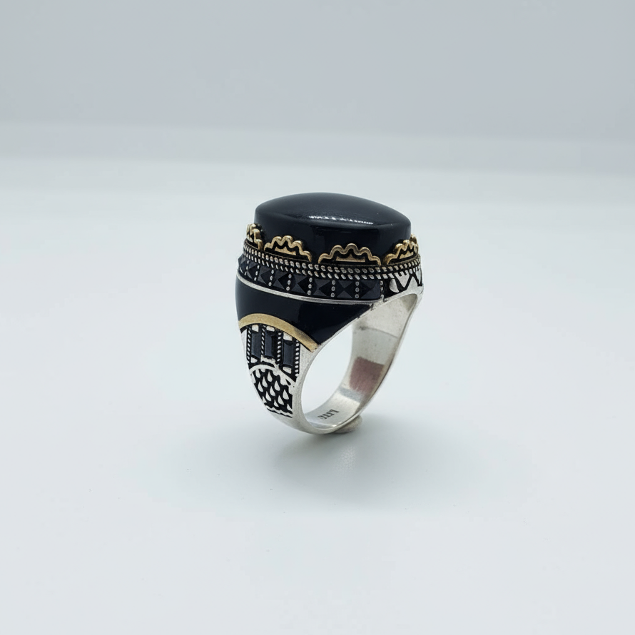 Silver ring with black stone and gold accents on a light gray background